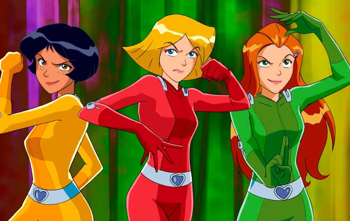 Personagens de Três espiãs demais! Uma mulher negra de cabelo preto curto e roupa amarela, uma loira de olho azul e roupa vermelha e uma ruiva com roupa verde.