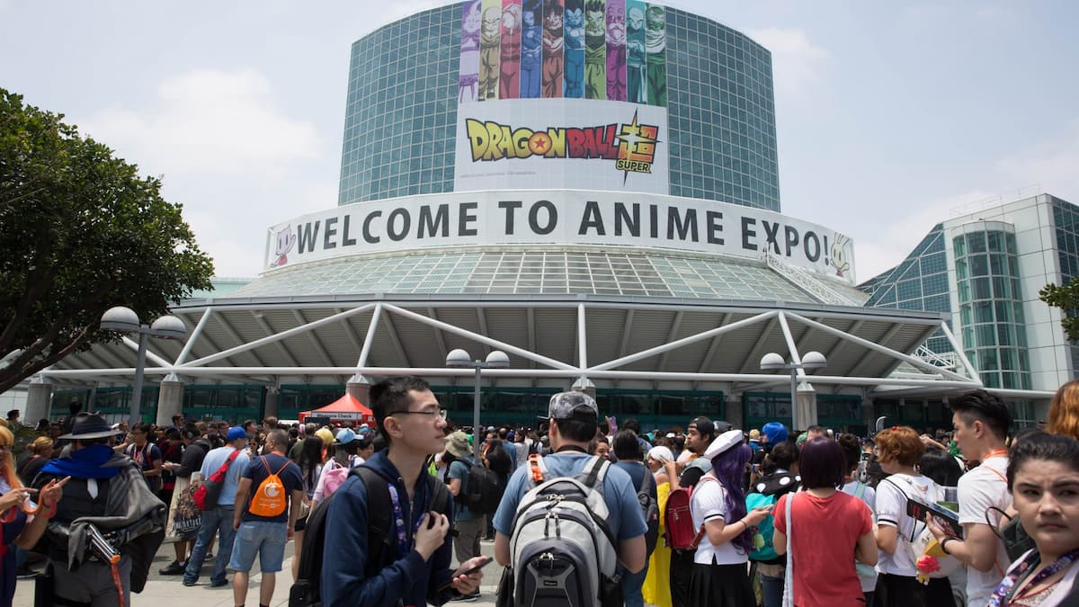 entrada de local de evento com banner escrito "welcome to anime expo" e várias pessoas aglomeradas