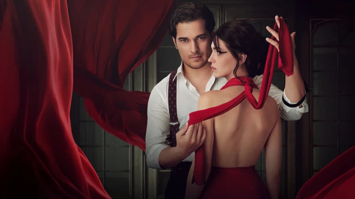 Homem segurando parte do vestido vermelho de uma mulher de costas para a câmera na série O Famoso Alfaiate.