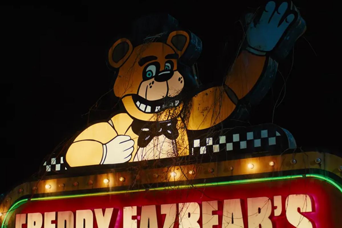 Cena do filme Five Nights at Freddy's, nela uma placa com o desneho de um urso na cor laranja é destacada ao centro.