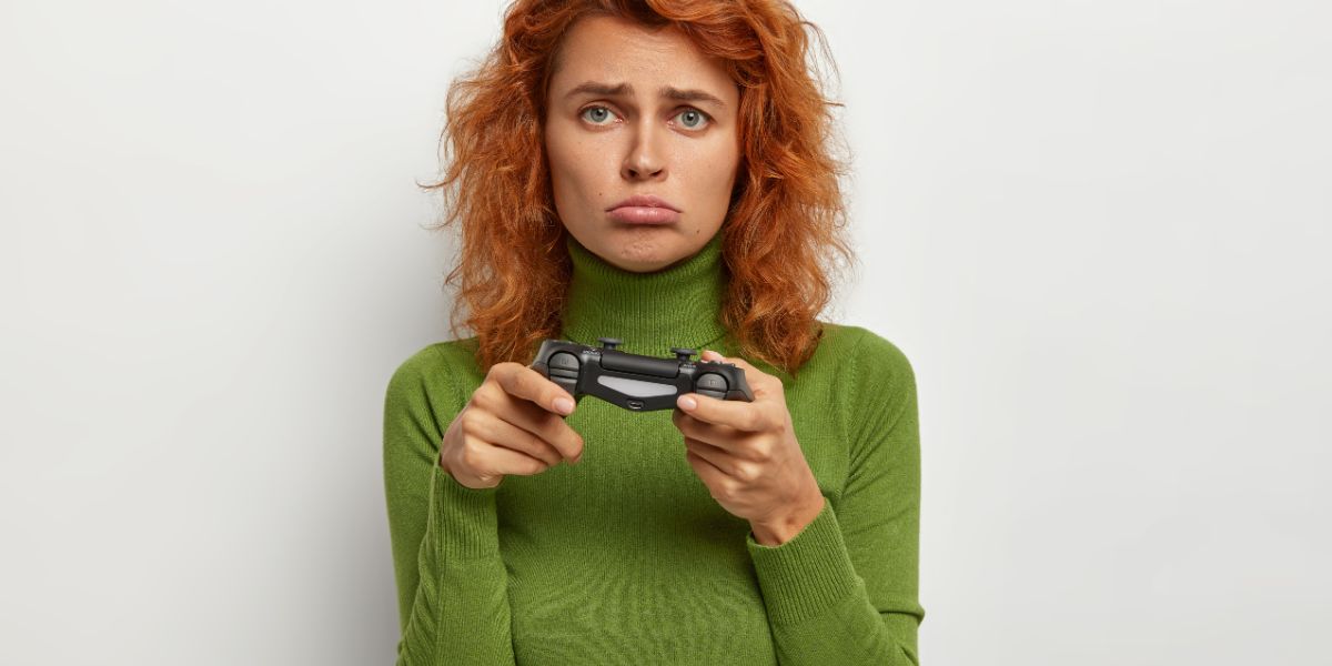 Mulher com um controle de videogame na mão e com expressão de infelicidade devido a um jogo ruim.