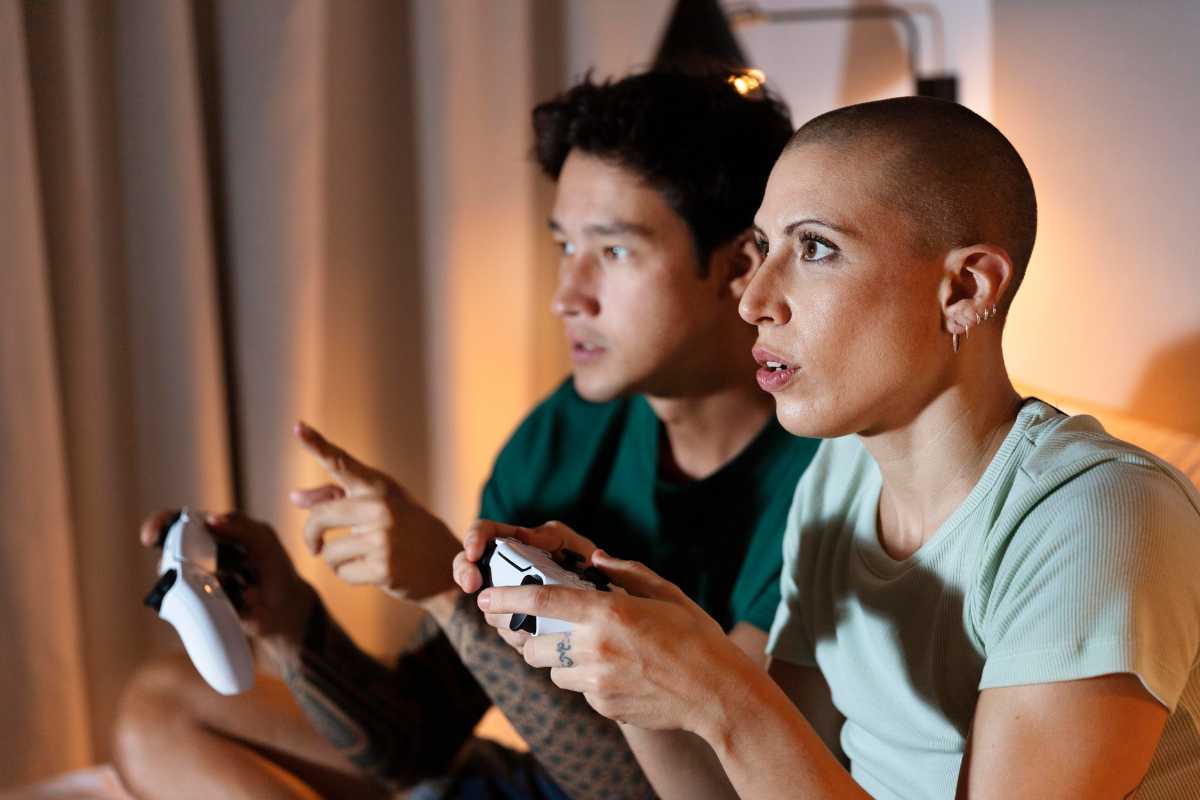 Homem e mulher segurando controle enquanto jogam videogame em uma sala de estar.