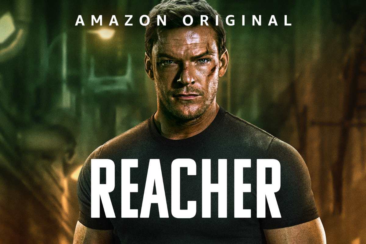 Reacher. Pôster de divulgação de Reacher. Nele, o protagonista está com um semblante sérioe algumas cicatrizes no rosto. SObre a imagem está escrito o "Reacher" e "Amazon Original".
