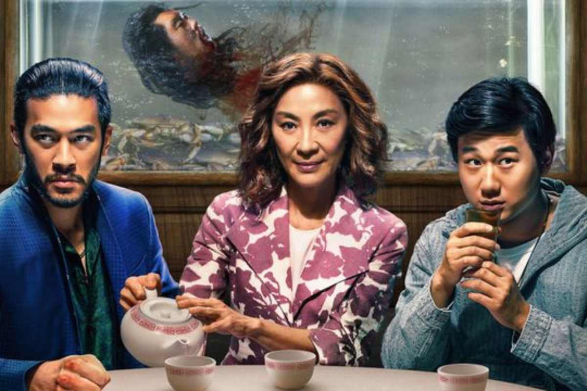 Irmãos Sun. Pôster de divulgação da série Irmãos Sun. Nele, os três protagonistas estão sentados à mesa, a mulher, que está ao centro, está servindo chá. Ao fundo, dentro de um aquário, há uma cabeça decapitada.